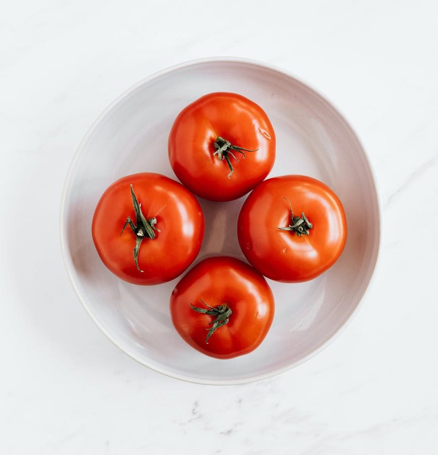 ripe tomatoes in ceramic bowl placed on marble table